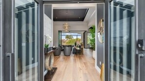 Ein modernes Interieur mit Holzboden, einer Sitzecke inklusive Tisch und Stühlen sowie einem großen Fenster mit Blick ins Freie.
