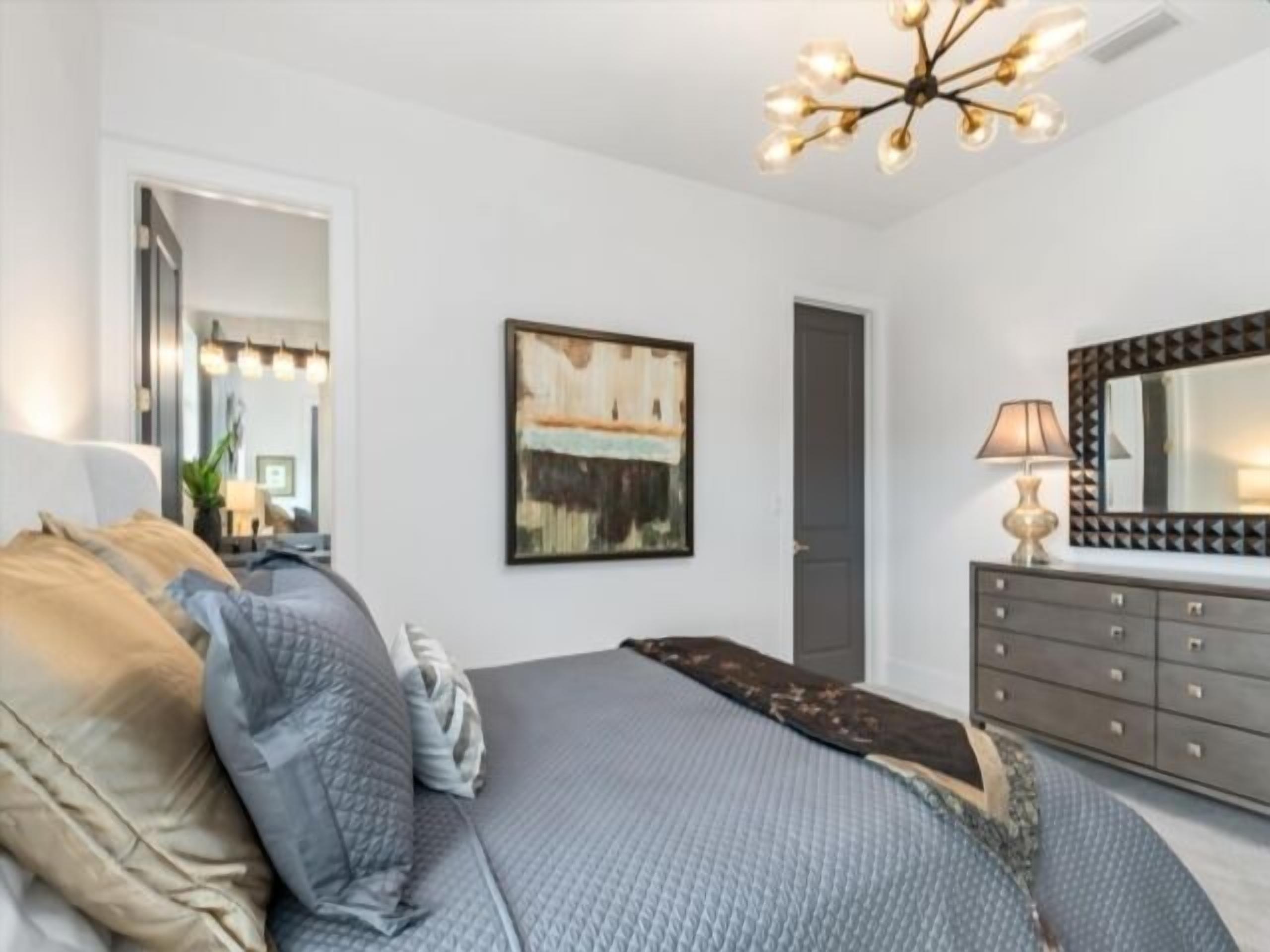 Un dormitorio con cama, cómoda, espejo y candelabro.
