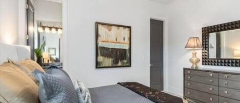Un dormitorio con cama, cómoda, espejo y candelabro.