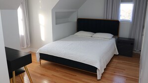 Een slaapkamer met een bed, een bureau en een raam.