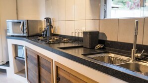 Une cuisine moderne équipée d’un évier en acier inoxydable, d’un four à micro-ondes et d’une machine à café.