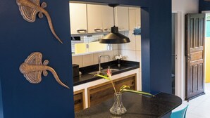 Une cuisine moderne avec des murs bleu foncé, un plan de travail noir et un luminaire suspendu.