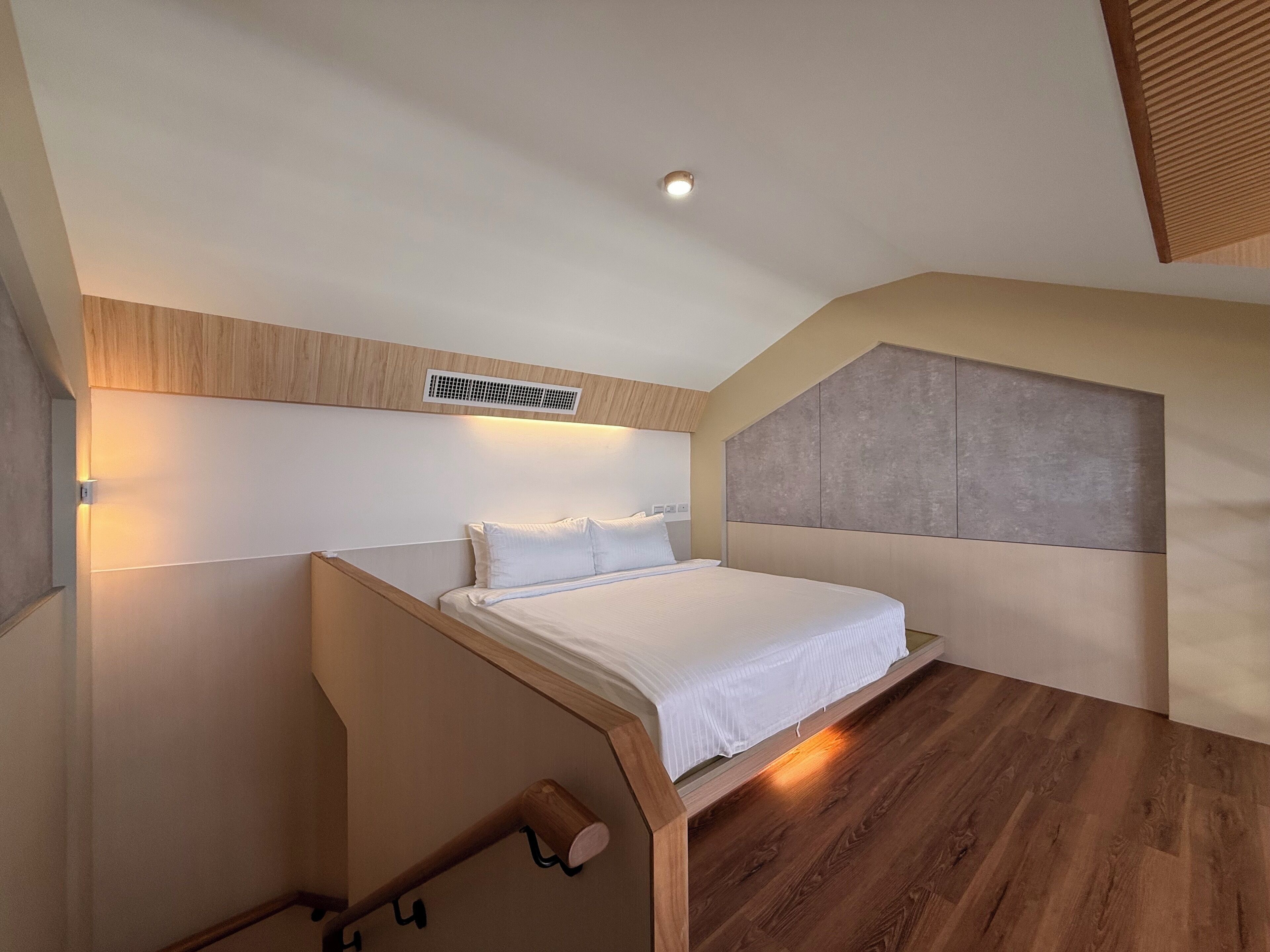 Un dormitorio moderno con cama, cabecero de madera e iluminación empotrada.