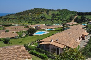 A residential area with terracotta-tiled roofs, a swimming pool, and lush greenery. - Villa with pool 300 meters from the sea - Ogliastra (Tertenia)