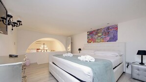 Een moderne slaapkamer met een groot bed, een kaptafel met spiegel en een kleurrijke muurschildering.