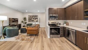 Eine moderne Küche mit Edelstahlgeräten, Holzschränken und einem Essbereich mit Sofa und Couchtisch.