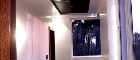 A modern hotel room with a large window, a bed, and a wooden ceiling.