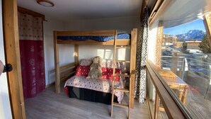 Een kamer met een stapelbed, een raam met uitzicht op een berg en een houten plafond.