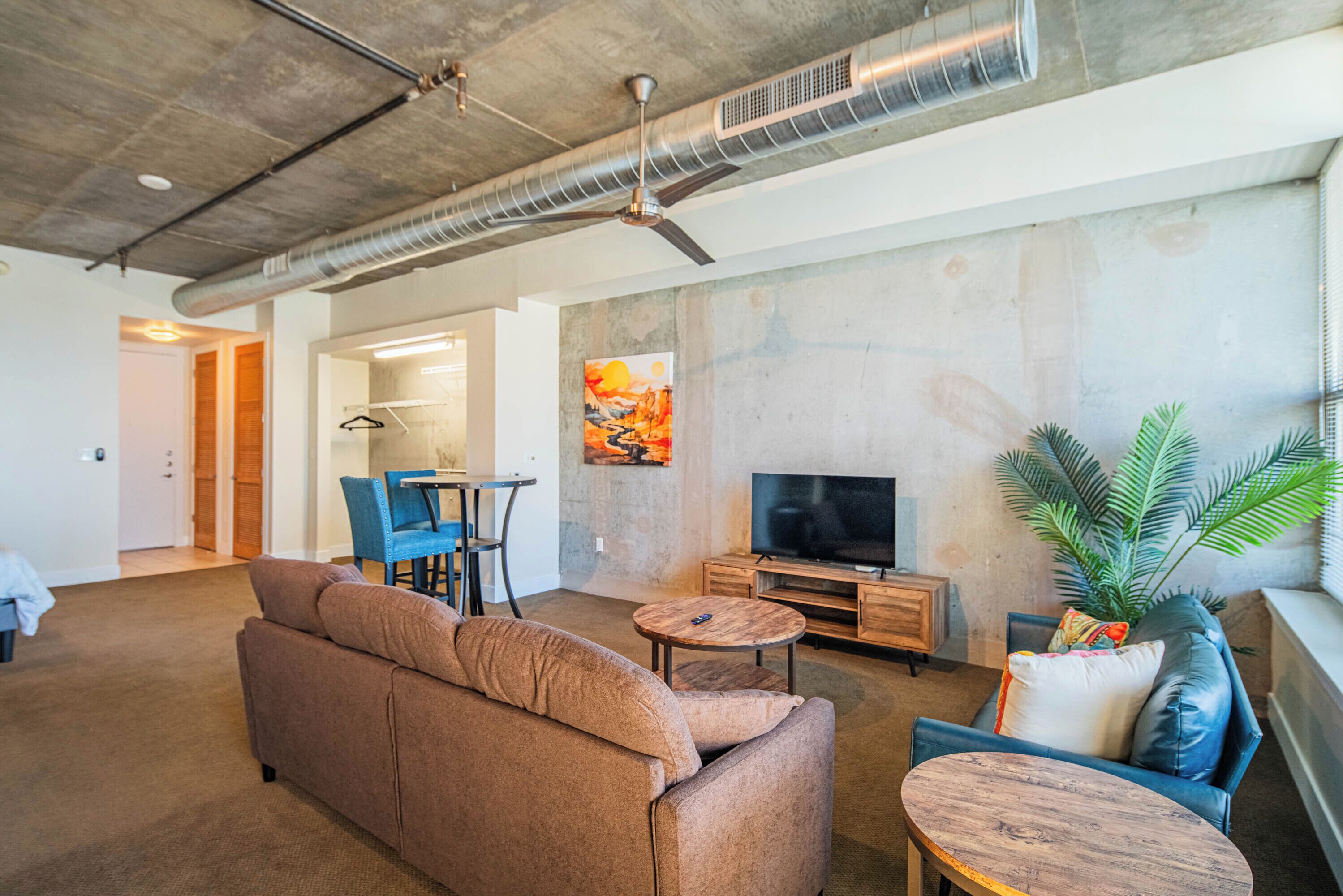 A modern living room with a sofa, a coffee table, a TV, and a plant.
