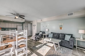 Ein modernes Wohnzimmer mit Essbereich, grauem Sofa und Deckenventilator.