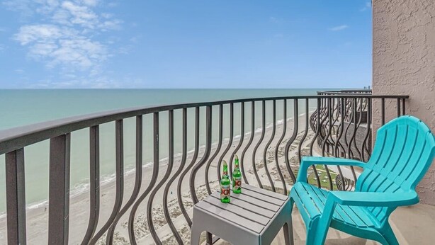 A balcony with a view of the beach, two green bottles, and a turquoise chair. - Palms Resort #1704: 2  BR, 2.5  BA Condominium in Myrtle Beach, Sleeps 6 (Myrtle Beach)