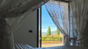 Ein Schlafzimmer mit einem großen Fenster, einem Bett und Blick auf einen Balkon mit Geländer.