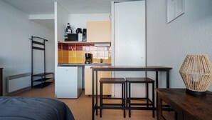 Ett litet, praktiskt pentry med kylskåp, mikrovågsugn och kaffebryggare. Där finns också ett litet bord med två pallar och en lampa.