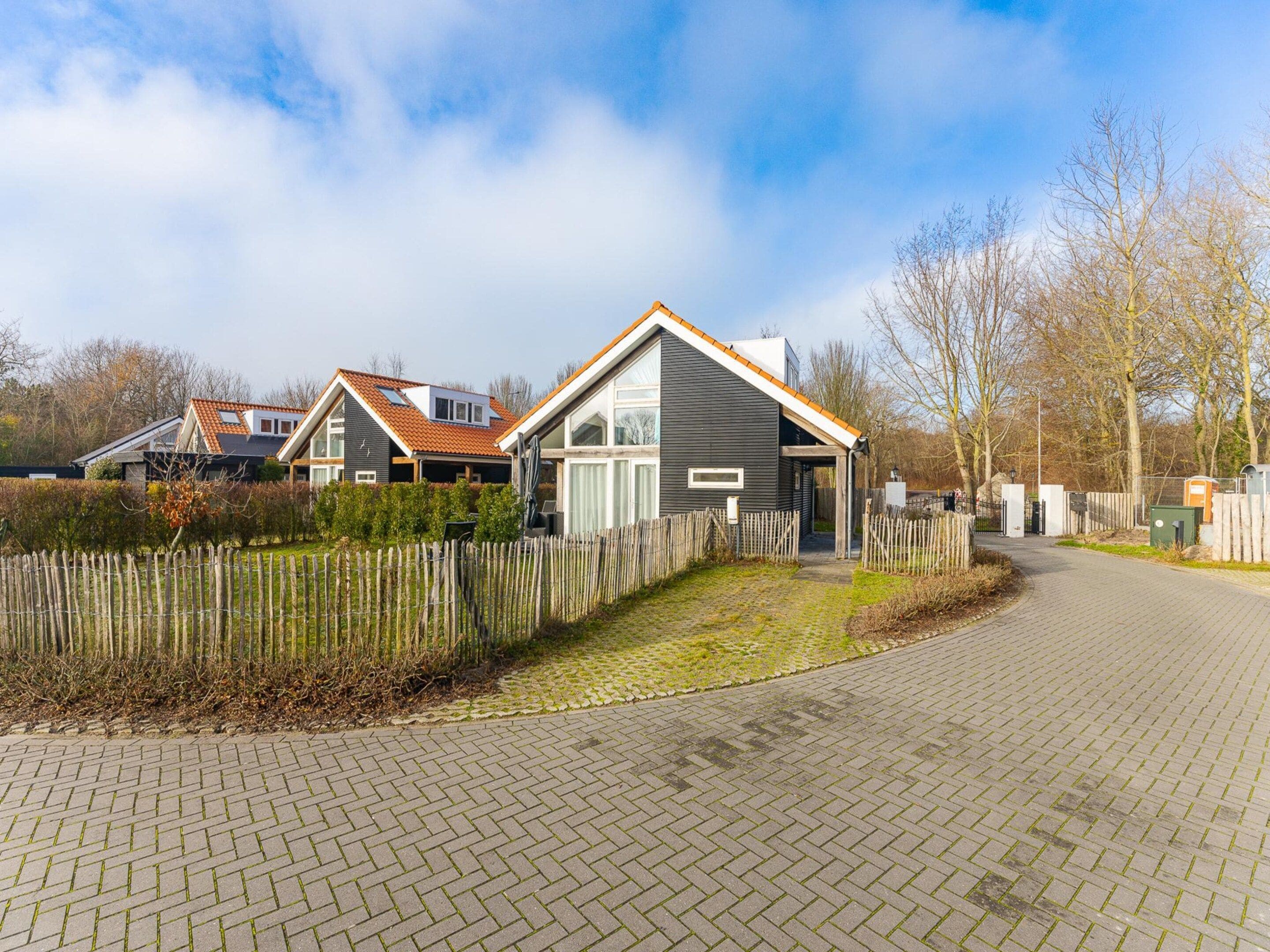 A residential area with houses, a paved driveway, and a wooden fence.