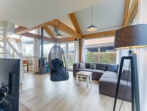 Un vaste espace de vie comprenant un fauteuil suspendu, un canapé, une table basse et un téléviseur.