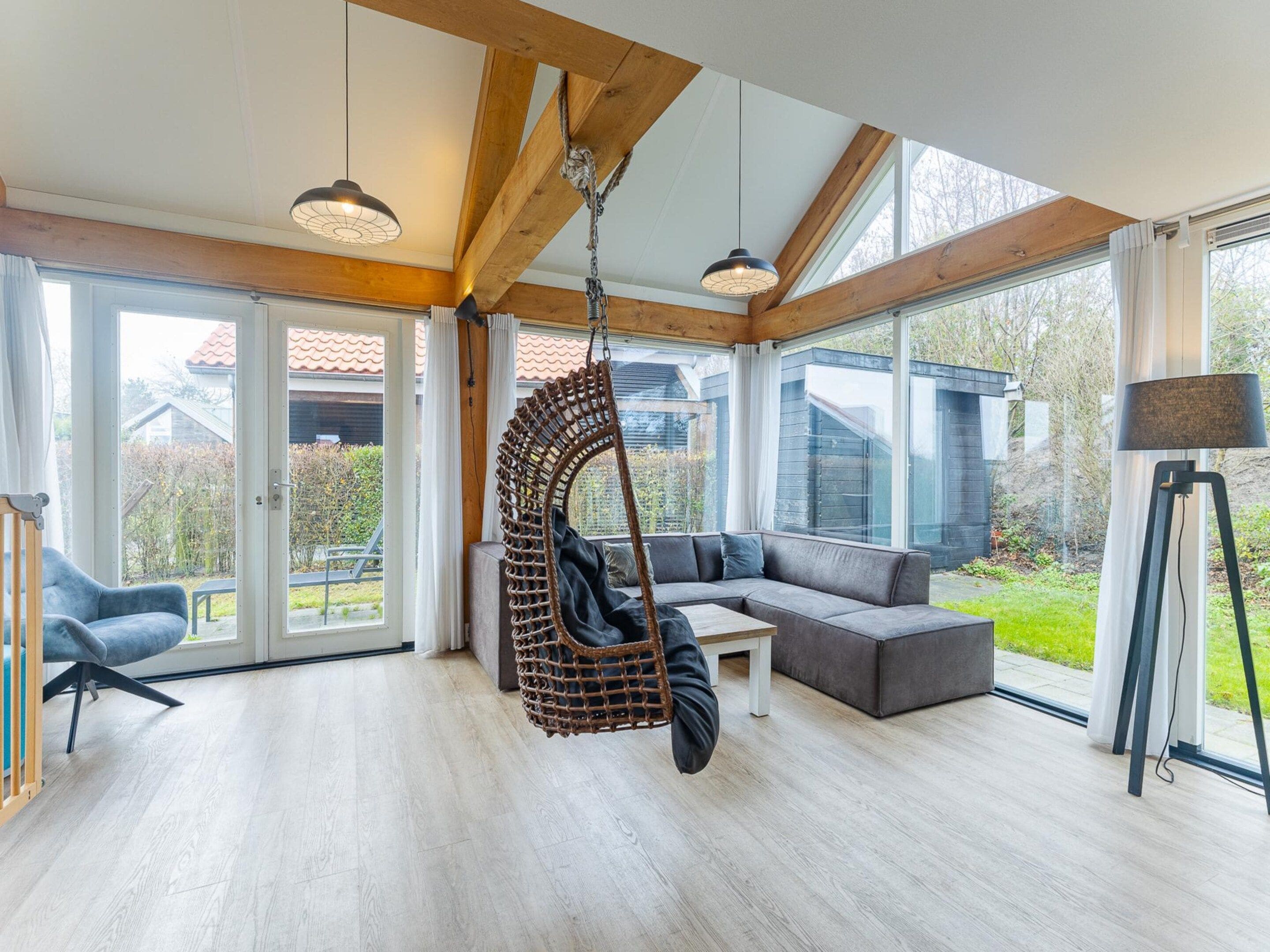 Une pièce spacieuse avec un fauteuil suspendu, un canapé et un lampadaire.