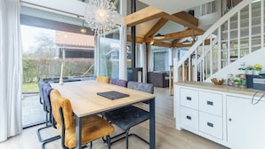 A modern kitchen with a wooden table, built-in cabinets, and a staircase leading to an upper level. - Coastal Family Escape With Enclosed Garden (Renesse)