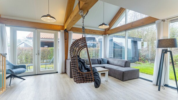 A spacious living room with a hanging chair, a sofa, and a coffee table. - Coastal Family Escape With Enclosed Garden (Renesse)