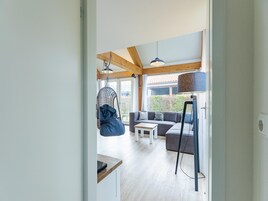 Un interior moderno con techo de madera, una silla colgante, un sofá, una mesa de centro y una lámpara de pie.