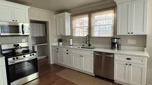 Una cocina moderna con armarios blancos, electrodomésticos de acero inoxidable y piso de madera.