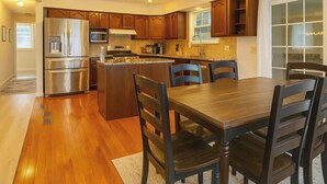 A modern kitchen with wooden cabinets, stainless steel appliances, and a central island with seating. - This house is a 3 bedroom(s), 2 bathrooms, located in Latham, NY. (Latham)