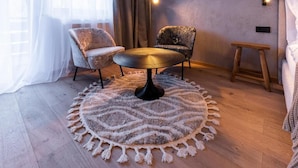 A room with a round table, two patterned armchairs, a wooden bench, and a decorative rug. - AFOCH FEI das Landhaus (Sankt Anton am Arlberg)
