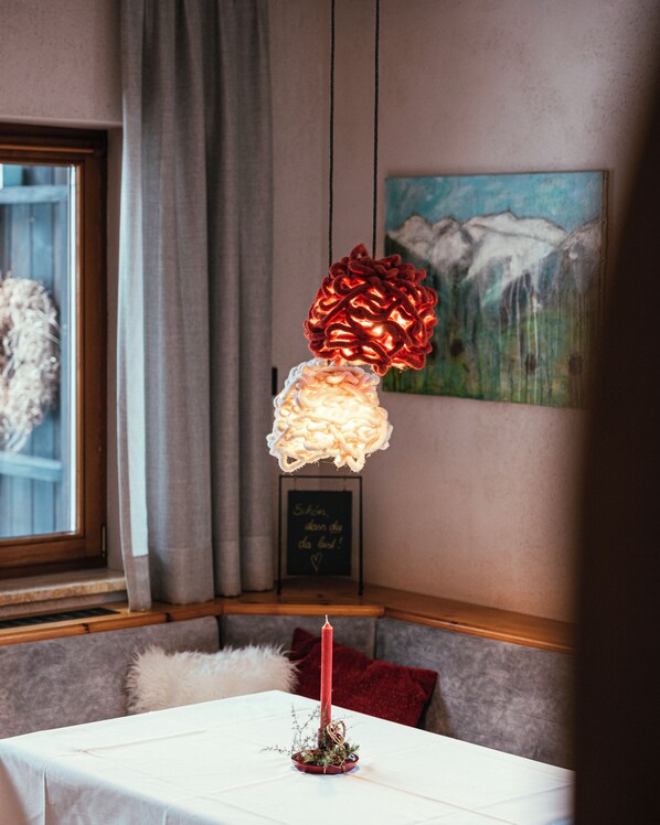 A room with a table set for dining, a candle, and a decorative item resembling a pine cone. - AFOCH FEI das Landhaus (Sankt Anton am Arlberg)