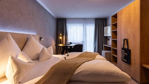 A hotel room with a large bed, a desk, and a TV. - AFOCH FEI das Landhaus (Sankt Anton am Arlberg)