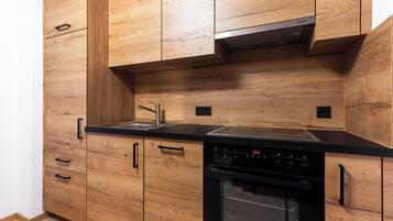 A kitchen with wooden cabinets, a black countertop, a stainless steel sink, and a built-in oven.