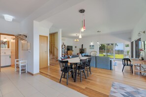 A spacious living area with a dining table, chairs, a sofa, and a kitchen in the background. - Sea Sky House By Holiday Rental Madeira (Ribeira Brava)