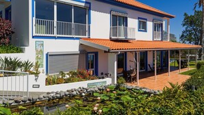 A modern two-story house with a covered patio, a small pond with water lilies, and a well-maintained garden. - Sea Sky House By Holiday Rental Madeira (Ribeira Brava)