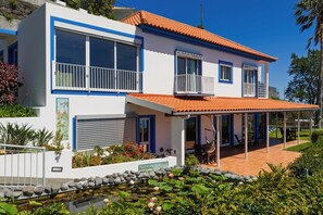 A modern two-story house with a covered patio, a small pond with water lilies, and a well-maintained garden. - Sea Sky House By Holiday Rental Madeira (Ribeira Brava)