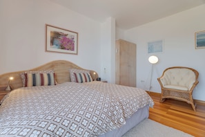 Een slaapkamer met een bed, een stoel, een kledingkast en een nachtkastje.
