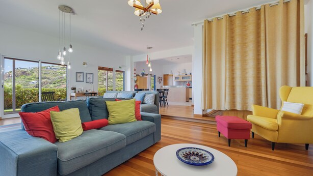 A modern living room with a sofa, a yellow armchair, a dining area, and a kitchen in the background. - Sea Sky House By Holiday Rental Madeira (Ribeira Brava)