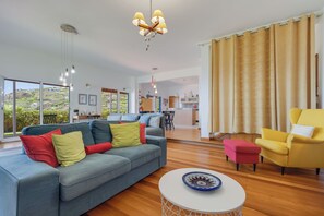 A modern living room with a sofa, a yellow armchair, a dining area, and a kitchen in the background. - Sea Sky House By Holiday Rental Madeira (Ribeira Brava)