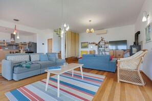 Un salon moderne avec un canapé, une table basse et un fauteuil en osier.