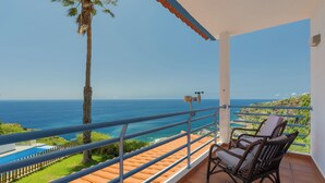Un balcón con vista al océano, una silla y una piscina pequeña.