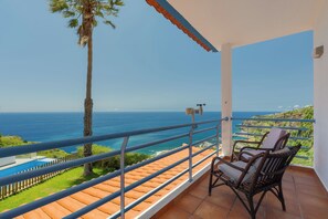 Un balcón con vista al océano, una silla y una piscina pequeña.