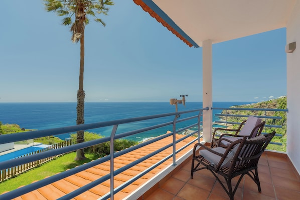 Un balcon avec vue sur l’océan, une chaise et une petite piscine.