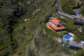 A hillside property with a house, a swimming pool, and solar panels. - Sea Sky House By Holiday Rental Madeira (Ribeira Brava)