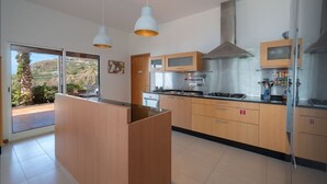 A modern kitchen with wooden cabinets, a stainless steel range hood, and pendant lighting. - Sea Sky House By Holiday Rental Madeira (Ribeira Brava)