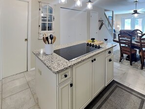 A kitchen with a granite countertop, white cabinetry, and a black induction cooktop. - Whispering Bluff #402 | Partial Mountain Views (Ruidoso)