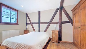 A bedroom with a large bed, wooden beams, a window with lace curtains, and a radiator. - La Perle du Ried N° 7 near Europapark - Typical Alsatian dovecotes (Boofzheim)