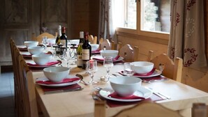 Mesa de comedor dispuesta con cuencos blancos, servilletas rojas y botellas de vino.