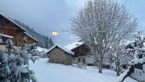 Un pueblo cubierto de nieve con casas de madera, un edificio de piedra y un cielo despejado.