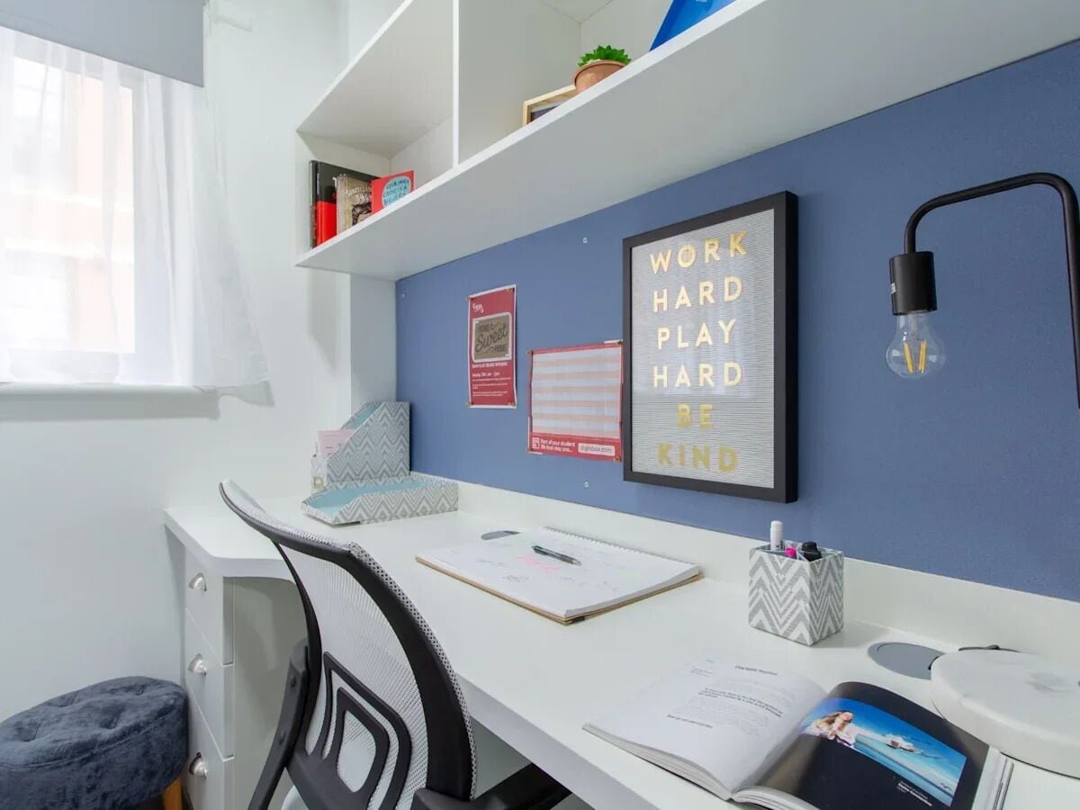 Un espace de travail bien aménagé, comprenant un bureau, une chaise et un tableau d’affichage en liège où sont accrochées des citations inspirantes.