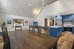 Une cuisine moderne avec des meubles bleus, une table à manger en bois et un grand îlot central.