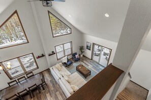A spacious loft-style living area with high ceilings, large windows, and a dining area.