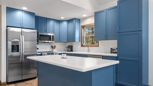 Une cuisine moderne avec des meubles bleus, des appareils en acier inoxydable et un îlot central.