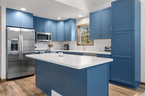 Une cuisine moderne avec des meubles bleus, des appareils en acier inoxydable et un îlot central.